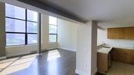 Located at 141 S Harrison St in East Orange, NJ, this multi-level space spans two floors and is designed with a clean, modern aesthetic. The main living area immediately draws attention with its expansive windows that frame views of the surrounding greenery, flooding the interior with abundant natural light throughout the day. Rich, dark hardwood flooring runs throughout, providing a warm contrast to the crisp white walls and light-toned structural columns that add architectural character to the open layout. The open-concept design seamlessly connects the living area to the kitchen space, which features cabinetry and a sink visible from the main room, creating a functional and cohesive flow. Baseboard heating is integrated along the windowed walls, ensuring year-round comfort. The neutral color palette of beige and white tones throughout the space lends a versatile, move-in-ready quality suitable for a variety of uses. Structural columns punctuate the open floor plan, adding visual interest without interrupting the sense of spaciousness. The two-floor configuration offers flexibility and separation of living or working areas, making this East Orange property a well-appointed and practical space.
