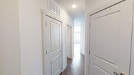This single-floor residence is designed with a contemporary aesthetic, combining clean lines, neutral tones, and quality finishes throughout. The standout feature is the expansive curved living room, where a sweeping wall of floor-to-ceiling windows and a glass-paned door floods the space with abundant natural light and provides broad outdoor views. Dark hardwood-style flooring runs throughout the main living areas, adding warmth and contrast to the crisp white walls.

The open-concept kitchen is equipped with stainless steel appliances, including a range, over-the-range microwave, and a French door refrigerator. Gray cabinetry with sleek hardware pairs with granite countertops and a subway tile backsplash, while a kitchen island with pendant lighting bridges the kitchen and living area.

The bedrooms feature soft carpeting and large windows fitted with blinds, maintaining a bright, airy atmosphere. Two bathrooms serve the unit — one offering a double-sink vanity with granite counters, dark cabinetry, and a walk-in tiled shower, and the other featuring a single vanity and a tiled tub-shower combination. A hallway with panel doors and overhead ventilation connects the spaces efficiently.