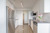 Located at 25 Fisherville Rd in North York, Toronto, this 2-bedroom, 1-bathroom unit offers a well-organized layout across a single floor. The combined living and dining area is a standout feature, with large floor-to-ceiling windows that flood the space with natural light and frame sweeping views of the Toronto skyline. Classic parquet wood flooring runs throughout the living areas and bedrooms, adding warmth and character to the clean, white-walled interior.

The kitchen is thoughtfully designed with white shaker-style cabinetry, a white subway tile backsplash, dark countertops, and a full suite of stainless steel appliances including a range, over-the-range microwave, dishwasher, and refrigerator. Light-toned tile flooring and recessed ceiling lighting complete the functional and modern aesthetic.

Both bedrooms are comfortably sized, featuring the same parquet flooring and bright white walls. The primary bedroom benefits from a large window with open city views and baseboard heating. The bathroom is finished with clean white subway tile surrounding a full soaker tub and shower combination with chrome fixtures. A hallway connects all rooms, contributing to the unit's efficient and practical flow.