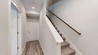This three-story townhome offers a functional and modern layout spread across three well-defined levels. The entry level welcomes you with wood-look flooring, a clean hallway, and a carpeted staircase with a sleek dark metal railing leading to the main living areas above.

The main floor serves as the heart of the home, featuring an open-concept kitchen and dining area alongside a spacious living room. The kitchen is outfitted with white shaker cabinetry, stainless steel appliances, a subway tile backsplash, and a large island with a dark countertop — ideal for both cooking and gathering. The adjoining dining area benefits from abundant natural light through multiple windows, while the living room features wood-look flooring, a ceiling fan, and a welcoming, neutral color palette.

Also on this floor is a dedicated office space with a bold accent wall and natural light from a large window — perfect for working from home. A full bathroom and a dedicated laundry room with a full-size washer and dryer round out this level.

The upper floor houses two generously sized bedrooms, including a spacious primary suite, along with additional bathrooms and closets. Throughout the home, neutral tones, consistent wood-look flooring, and recessed lighting contribute to a cohesive, contemporary aesthetic.