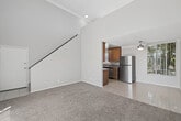 Located at 16801 Vanowen St in the Van Nuys neighborhood of Los Angeles, this two-story residence offers a well-organized split-level layout across two floors. The main level provides the larger share of the living space and includes a bright living area with soaring vaulted ceilings and a full-height sliding glass door that fills the room with natural light and opens to an outdoor view. Light-colored carpet adds warmth underfoot throughout the living and bedroom areas. An adjoining dining area features tile flooring, a ceiling fan, and a window with vertical blinds. The galley-style kitchen is well-appointed with warm wood cabinetry, granite countertops, tile flooring, and a full suite of stainless steel appliances including a gas range, built-in microwave, dishwasher, and refrigerator. The full bathroom is finished with tile flooring, a wood vanity with granite countertop, and a tub/shower combination. The upper floor hosts the carpeted bedroom, which offers a comfortable and generously sized retreat with a window overlooking greenery and a mirrored sliding-door closet. An open loft-style landing connects the two floors via a staircase, offering additional flexible space. Neutral tones and clean finishes are consistent throughout the home.