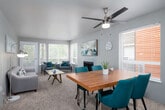 This single-floor residence offers a thoughtfully designed layout with a comfortable, cohesive aesthetic throughout. The open living and dining area serves as the heart of the home, featuring plush carpeting, a ceiling fan with light fixture, and a tiled fireplace as a central focal point. Large windows on multiple walls flood the space with natural light and provide views of surrounding greenery, while a glass door leads to a private balcony. The dining area accommodates a full-sized table with ease, flowing naturally into the living space.

The kitchen is well-equipped with two-tone cabinetry — crisp white upper cabinets paired with gray lower cabinets — complemented by light stone countertops and durable wood-look flooring. Stainless steel appliances, including a refrigerator, range, and dishwasher, complete the functional and stylish cooking space.

The primary bedroom is generously sized with soft carpeting, a large window, and ample room for a full furniture suite. A second bedroom offers versatility, ideal as a guest room or home office, with its own window and carpet flooring. The bathroom features a granite-style countertop with an undermount sink. An in-unit laundry closet with a full-sized washer and dryer adds everyday convenience.