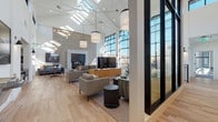 Located at 5400 S Park Terrace Ave in Greenwood Village, Colorado, this single-floor community space is a striking example of contemporary design that seamlessly blends openness, functionality, and style. The centerpiece of the space is a dramatic great room boasting soaring vaulted ceilings lined with skylights, flooding the interior with abundant natural light. Towering floor-to-ceiling black-framed windows frame outdoor views and lend an industrial-modern aesthetic throughout.

A grand stone fireplace wall anchors the main lounge area, where multiple seating arrangements invite relaxed conversation or casual gatherings. Light hardwood flooring flows continuously throughout, unifying each distinct zone. A dedicated games room features a shuffleboard table, large-screen TVs, and generous lounge seating bathed in natural light from expansive windows.

A secondary lounge area offers a more intimate setting, highlighted by a dramatic textured stone accent wall and sophisticated sectional seating. The workspace area is thoughtfully designed with built-in shelving, dual workstations, and a warm copper pendant light, all positioned beneath clerestory windows. A bright, open dining and kitchen area completes the space, featuring subway tile, pendant lighting, and a welcoming communal table — ideal for social gatherings and everyday use.