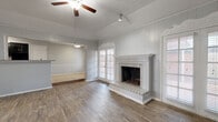 Located at 8623 Starcrest Dr in San Antonio, Texas, this single-story, 2-bedroom, 4-bathroom home offers a well-designed layout with comfortable living spaces throughout. The expansive living room is a standout feature, showcasing wood-look flooring, a tray ceiling with a ceiling fan, a classic brick fireplace, and built-in shelving with cabinetry. Natural light filters in through window blinds, creating a bright and welcoming atmosphere. An adjacent room provides additional flexible living space, also finished with matching wood-look floors, a ceiling fan, and generous windows overlooking the outdoors. The galley-style kitchen is thoughtfully appointed with dark cabinetry, mosaic tile backsplash, light countertops, tile flooring, and black appliances including a refrigerator and electric range. A breakfast bar area connects the kitchen to the main living spaces. The spacious primary bedroom features wood-look flooring, a ceiling fan, and ample natural light from dual windows. The four bathrooms include both tub-shower combinations with white tile surrounds and a walk-in shower, all finished with tile flooring and chrome fixtures. Outdoors, a covered brick patio with a decorative brick perimeter wall provides a private, shaded retreat. Textured ceilings are present throughout the home.