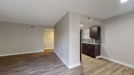 This single-floor residence offers a thoughtfully designed layout that balances comfort and functionality. Rich wood-look flooring flows consistently throughout the space, complementing the neutral gray wall tones and clean white baseboards that define each room.

The kitchen is a standout feature, outfitted with deep espresso-toned cabinetry that extends to the ceiling for generous storage, light granite-style countertops, a stainless steel refrigerator, and a striking mosaic tile backsplash that adds texture and visual interest. The kitchen connects seamlessly to the main living area, which is anchored by a textured ceiling and benefits from abundant natural light through multiple windows fitted with horizontal blinds.

A sliding glass door in the living area opens to a private balcony, extending the living space outdoors and allowing for excellent airflow and light. The bedroom spaces are generously proportioned, each featuring wood-look flooring, neutral walls, and windows that invite natural light. One bedroom includes a dedicated walk-in closet with built-in shelving, providing ample storage.

The bathroom is cleanly finished with a tiled shower-tub surround, wood-look flooring, and a dark vanity with a granite-style countertop, maintaining the cohesive design language found throughout the residence.