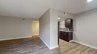 This single-floor residence offers a thoughtfully designed layout that balances comfort and functionality. Rich wood-look flooring flows consistently throughout the space, complementing the neutral gray wall tones and clean white baseboards that define each room.

The kitchen is a standout feature, outfitted with deep espresso-toned cabinetry that extends to the ceiling for generous storage, light granite-style countertops, a stainless steel refrigerator, and a striking mosaic tile backsplash that adds texture and visual interest. The kitchen connects seamlessly to the main living area, which is anchored by a textured ceiling and benefits from abundant natural light through multiple windows fitted with horizontal blinds.

A sliding glass door in the living area opens to a private balcony, extending the living space outdoors and allowing for excellent airflow and light. The bedroom spaces are generously proportioned, each featuring wood-look flooring, neutral walls, and windows that invite natural light. One bedroom includes a dedicated walk-in closet with built-in shelving, providing ample storage.

The bathroom is cleanly finished with a tiled shower-tub surround, wood-look flooring, and a dark vanity with a granite-style countertop, maintaining the cohesive design language found throughout the residence.