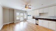 Located at 755 E Broad St in Athens, GA, this single-floor, 2-bedroom, 2-bathroom unit offers a well-organized layout across a compact yet efficient footprint. The open living and kitchen area is anchored by light hardwood floors, crown molding, and a ceiling fan with light fixture. A pair of windows with blinds floods the space with natural light and provides views of the surrounding neighborhood. The kitchen is outfitted with white raised-panel cabinetry, dark granite countertops, a double stainless steel sink, and a full suite of stainless steel appliances including a refrigerator, range, microwave, and dishwasher. A charming arched architectural detail adds character to the kitchen's transition into the living area. Two hallways with recessed lighting and clean white baseboards connect the living spaces to the bedrooms and bathrooms. Both bedrooms feature plush carpet flooring, neutral-toned walls, ceiling fans, and windows with blinds offering outdoor views. The primary bedroom includes a closet and access to an additional door. Both bathrooms are finished with warm earth-toned stone tile floors and tub/shower surrounds, white vanities with dark granite countertops, and brushed nickel fixtures, creating a cohesive and polished aesthetic throughout.