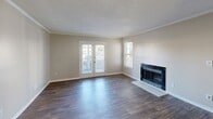Located at 2495 Meadowridge Ln in Montgomery, Alabama, this single-story, 3-bedroom, 2-bathroom home offers a well-organized and functional layout. The living room is a standout space, featuring rich dark hardwood-style flooring, crown molding, a textured ceiling, and a fireplace framed by a clean white hearth. French doors flood the room with natural light and provide direct access to the covered patio, which overlooks the surrounding neighborhood. Adjacent to the living room, the dining area continues the hardwood-style flooring and is distinguished by an elegant chandelier and crown molding, creating a polished, cohesive feel. A pass-through connects the dining space to the kitchen, which is equipped with white cabinetry, light stone countertops, and black appliances including a range, over-the-range microwave, and refrigerator, all set atop durable wood-look flooring. The three bedrooms are carpeted and well-lit with natural light from large windows. The primary bedroom offers generous proportions and direct outdoor access. Both bathrooms include tub-shower combinations, vanities with stone-look countertops, and wood-style flooring. A dedicated laundry room and seven closets throughout provide ample storage across the home.