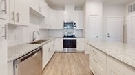 Located at 101 Ascend Loop in Myrtle Beach, South Carolina, this well-appointed single-story residence combines modern design with functional living spaces throughout. The open-concept layout seamlessly connects the kitchen and living area, creating an inviting flow ideal for everyday living and entertaining. The gourmet kitchen is a standout feature, showcasing crisp white shaker cabinetry, lustrous granite countertops, a large central island with pendant lighting, a subway tile backsplash, and a full suite of stainless steel appliances including a refrigerator, range, microwave, and dishwasher. Wood-look plank flooring runs through the main living areas, complemented by a ceiling fan and abundant natural light from multiple windows and a glass-panel door. The bedrooms are finished with plush carpeting and feature generous closet space, including a walk-in closet with wire shelving in the primary suite. The primary bathroom offers a granite-topped dual vanity with white cabinetry, a soaking tub, and a glass-enclosed shower. A secondary bathroom provides additional convenience with matching finishes. A dedicated laundry area with stacked washer and dryer rounds out the well-designed interior of this move-in-ready Myrtle Beach home.