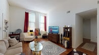 This 2-bedroom, 2-bathroom unit in Building 2203 is a single-floor residence defined by notable architectural character and functional layout. The living room serves as a welcoming centerpiece, showcasing soaring ceilings, warm hardwood flooring, and tall windows dressed with bold curtains that flood the space with natural light. A textured, whitewashed exposed brick wall adds a distinctive industrial charm, complementing the open and airy atmosphere.

Adjacent to the living area, a dedicated dining space provides a clean, defined area for meals, with a window offering additional natural light. The galley-style kitchen is efficiently arranged with ample white cabinetry, generous countertop space, a double-basin sink, and direct access to the unit's entry door.

Both bedrooms are comfortably sized, each featuring hardwood floors and windows with natural light. The rooms offer sufficient space for standard bedroom furnishings. The two bathrooms are functional and well-appointed, one featuring a shower-tub combination with a classic tile-patterned curtain and wood-accented fixtures.

Overall, the unit presents a cohesive blend of classic architectural details—particularly the exposed brick and high ceilings—with practical living spaces suited for everyday comfort.