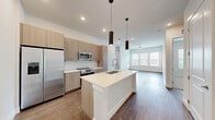 Located at 604 Vistera Blvd in North Venice, FL, this thoughtfully designed single-floor residence offers a seamless blend of modern aesthetics and functional living. The open-concept great room unifies the dining area, kitchen, and living room into a bright, cohesive space highlighted by warm wood-look flooring and recessed lighting throughout. The gourmet kitchen is a standout feature, showcasing light wood cabinetry, a white quartz waterfall island with an undermount sink, stainless steel appliances including a side-by-side refrigerator and range, a subway tile backsplash, and striking cylindrical pendant lights overhead. The living area extends toward large windows fitted with blinds, filling the space with natural light. The primary bedroom features plush carpeting, dual windows with outdoor views, and two closets for ample storage. A versatile den provides additional flexible living space. The bathroom is finished with a quartz-topped double vanity, an illuminated mirror, and a soaking tub with white subway tile surround. Additional conveniences include a dedicated laundry area and a private patio. Clean white walls and consistent finishes throughout create a bright, cohesive ambiance suited for comfortable Florida living.