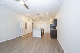 This two-story home offers a thoughtfully designed layout that blends modern finishes with functional living spaces. The main level greets visitors with a bright, open entryway featuring light wood-look flooring and a staircase with white railings leading to the upper level. The open-concept kitchen and living area is a standout, showcasing dark espresso cabinetry, granite countertops, a large central island with a built-in sink and dishwasher, and a full suite of stainless steel appliances including a refrigerator, microwave, and range. Stylish pendant lights hang above the island, complementing the recessed lighting throughout. The spacious living area flows seamlessly from the kitchen and is equipped with a ceiling fan. The main level also includes a bathroom featuring a dark vanity with granite countertop and a tub-shower combination. Upstairs, the bedrooms are generously sized, each carpeted and filled with natural light from multiple windows fitted with blinds, and each equipped with a ceiling fan. The upper-level bathrooms mirror the home's consistent aesthetic, featuring dark vanities with granite countertops and tub-shower combinations with clean tile surrounds. Throughout, neutral warm-toned walls and light flooring create a cohesive, inviting atmosphere.