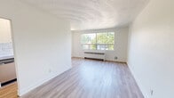 This 2-bedroom, 1-bathroom unit at 318-352 Patricia Ave in Kitchener, Ontario offers a clean, functional layout across a single floor. The open living room features light hardwood flooring, crisp white walls, and a decorative textured ceiling, creating a bright and airy atmosphere. A wide window frames lush, tree-lined street views, with a classic radiator unit beneath providing efficient heating. The separate kitchen is accessed through a clean-cut doorway and is equipped with stainless steel appliances including a full-size refrigerator and dishwasher, complemented by white cabinetry and a tile backsplash. The primary bedroom offers a comfortable footprint, a double-door closet, and access to the hallway connecting the rest of the unit. The second bedroom also benefits from generous natural light through a large window overlooking mature trees. Both bedrooms continue the consistent light hardwood flooring found throughout. The bathroom is finished with classic white subway tile surrounding a full bathtub and shower combination, paired with chrome fixtures for a timeless, clean aesthetic. A connecting hallway ties all rooms together efficiently. The overall design is minimal and well-maintained, offering a bright, move-in ready living space.