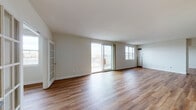 Located at 50 Park Row W in Providence, Rhode Island, this single-floor unit offers a clean, contemporary design throughout. Rich hardwood-style flooring runs continuously across the living spaces, lending warmth and visual cohesion to the interior.

The spacious main living area is highlighted by large sliding glass doors that open onto a private balcony, offering sweeping views of the Providence cityscape and green spaces below. Abundant natural light floods the room through expansive windows, creating an airy, open atmosphere. A charming French door adds a classic architectural detail, separating spaces while maintaining an open feel.

The galley-style kitchen is efficiently designed with white cabinetry, stainless steel appliances including a full-size refrigerator, a dark tile backsplash, and neutral countertops — providing both style and functionality. A pass-through window connects the kitchen to the main living space, enhancing the open layout.

Two well-appointed bathrooms feature white vanities with neutral countertops, large mirrors, and a combination tub/shower. One bathroom includes a dedicated laundry area with an in-unit washer, adding everyday convenience. The bedrooms are bright and clean-lined with white walls and warm flooring, offering flexible, versatile spaces. The overall ambiance is modern, light-filled, and move-in ready.