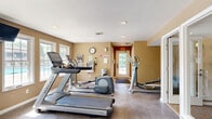 Located at 101 Forest Pkwy in Valley Park, Missouri, this single-floor fitness center offers a thoughtfully designed space dedicated to health and wellness. The exercise room is the centerpiece of the facility, bathed in natural light streaming through multiple large, white-trimmed windows that provide views of the surrounding outdoor area. Warm beige walls and recessed ceiling lighting create an inviting, energetic atmosphere throughout.

The exercise room is well-appointed with a varied selection of cardio equipment, including treadmills and elliptical machines, as well as a multi-station strength training unit with a weight bench. A full-length wall mirror spans one side of the room, enhancing the sense of openness and allowing users to monitor their form during workouts. Durable, easy-to-clean flooring runs throughout the exercise area, practical for high-traffic fitness use. A wall clock and mounted equipment panels keep the space functional and organized.

Entry to the facility is through a glass-paneled door, with clear sightlines across the workout floor. The facility also includes two restrooms — designated men's and women's — each finished with earthy-toned walls, stone-look tile flooring, and ADA-compliant grab bars for accessibility. Together, these amenities make this fitness center a complete and practical wellness facility.