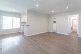Located on Killion Street in Los Angeles, California, this single-floor unit offers a clean, functional layout with a warm and inviting aesthetic throughout. Warm-toned wood-look flooring runs continuously across the living areas, complementing the light gray walls and crisp white baseboards that give the space a fresh, modern feel.

The open living area is bright and airy, illuminated by recessed ceiling lights and a window that invites natural light and views of the surrounding neighborhood. A wall-mounted heating and cooling unit ensures year-round comfort. The space flows naturally toward the kitchen, which features white cabinetry with brushed nickel hardware extending to the ceiling for ample storage, a gas range with a stainless steel vent hood, and a countertop with an integrated sink. The kitchen's efficient layout and generous cabinetry make it well-suited for everyday use.

A separate bedroom offers a quiet retreat with large windows dressed in vertical blinds, allowing natural light to fill the room throughout the day. The full bathroom is well-appointed with a tub-and-shower combination enclosed by sliding glass doors, white subway tile surround, a single vanity with a stone-look countertop, and a framed mirror with overhead lighting, creating a clean and practical space.