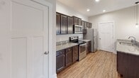 Located at 1125 Old Graves Mill Rd in Lynchburg, Virginia, this single-floor residence offers a well-designed, open-concept layout with a clean, contemporary aesthetic throughout. The living area is generously proportioned, featuring warm hardwood-style flooring, a ceiling fan, and a built-in fireplace that serves as a focal point of the space. A sliding glass door allows natural light to fill the room and provides access to the outdoors. The kitchen is thoughtfully appointed with dark espresso cabinetry, granite countertops, stainless steel appliances including a range, microwave, and refrigerator, and a peninsula with pendant lighting overhead that connects seamlessly to the main living area. The bedrooms are carpeted and well-sized, each equipped with a ceiling fan and windows with blinds that allow for natural light and privacy. Closet access is available in the bedrooms, with at least one featuring a connected en-suite bathroom. The bathrooms are finished with dark vanity cabinetry, white countertops, tile flooring, and a full soaking tub with a shower surround. Neutral wall tones throughout the residence create a cohesive and inviting atmosphere, making the space move-in ready and highly adaptable to a variety of interior styles.
