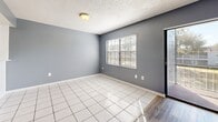 Located at 180 Royal Palm Dr in Kissimmee, FL, this well-laid-out 2-bedroom, 2-bathroom home offers a comfortable and functional single-floor living experience. The open-concept living, dining, and kitchen area forms the heart of the home, finished with a mix of wood-look and tile flooring beneath a textured ceiling. Cool-toned gray walls run throughout, creating a cohesive and modern aesthetic. A striking row of mirrored panels lines one wall of the living area, amplifying natural light and adding visual depth to the space. Sliding glass doors lead to a private balcony, bringing in abundant natural light and outdoor views. The kitchen is well-appointed with white cabinetry, subway tile backsplash, granite-style countertops, a peninsula for added workspace, and black appliances including a refrigerator, dishwasher, and range. A tray ceiling with overhead lighting adds architectural interest to the kitchen area. Both bedrooms feature soft carpeting, gray walls, and access to closets, including a walk-in closet with shelving. The bathrooms are cleanly finished with tile surrounds, a tub-shower combination, and vanity storage. Three closets throughout provide ample storage for everyday living.