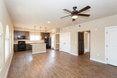 Located at 780 W Cherry Ln in Carlsbad, New Mexico, this single-story home offers a well-designed open-concept layout with a cohesive blend of functional and aesthetic details throughout. The kitchen serves as a central hub of the home, showcasing dark espresso cabinetry, a large center island with a light countertop and built-in outlets, pendant lighting, and black appliances including a range, microwave, and refrigerator. A window above the sink allows natural light to fill the space, while rich hardwood-style flooring extends through the kitchen and into the adjoining living areas. The living room is highlighted by a set of arched windows that invite abundant natural light and a ceiling fan overhead. A back door provides additional access to the exterior. Convenient built-in shelving offers open storage near the kitchen, complemented by a set of elegant double doors with arched panel detailing. The bedroom features plush carpeting, multiple windows, and sliding glass door access to a private balcony with exterior views, adding a desirable outdoor connection. Double closet doors with matching arched detailing provide generous storage. Neutral warm-toned walls and consistent trim work throughout the home create a clean, cohesive ambiance well-suited for comfortable everyday living.