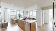 Located at 955 Eleventh Avenue in San Diego's vibrant Little Italy neighborhood, this two-bedroom, one-bathroom residence offers a thoughtfully designed open-concept layout with a refined modern aesthetic. The combined kitchen and living area serves as the heart of the home, anchored by a sleek island with a quartz countertop, warm wood cabinetry, stainless steel appliances, and light hardwood flooring that runs throughout. Floor-to-ceiling windows frame sweeping panoramic views of the San Diego skyline and cityscape, flooding the living space with abundant natural light. The dining area, seamlessly integrated into the open-plan layout, takes full advantage of the breathtaking city vistas. Both bedrooms continue the floor-to-ceiling window theme, offering impressive elevated views of the surrounding urban landscape. The second bedroom includes a built-in closet with sliding mirror doors, adding practical storage. The bathroom features elegant marble-style tile surrounding the tub and shower, paired with clean, neutral finishes. The overall ambiance is bright, airy, and contemporary, with a cohesive design language that balances modern functionality with high-rise living at its finest in downtown San Diego.