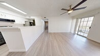 Located at 13150 Wenonah Ave SE in Albuquerque, New Mexico, this single-story 2-bedroom, 1-bathroom home offers a clean, modern aesthetic throughout. The open-concept living area features light wood-look plank flooring, crisp white walls, a textured ceiling, and a ceiling fan with light fixture. A sliding glass door and large window flood the living room with natural light and provide access to an outdoor area. The kitchen is thoughtfully designed in a galley style, featuring two-toned cabinetry with white upper cabinets and slate-gray lower cabinets, white quartz countertops, stainless steel appliances including a range, microwave, and refrigerator, and a stainless steel sink. A peninsula counter separates the kitchen from the living area, enhancing the open flow. Both bedrooms are carpeted and bright, with the primary bedroom offering a generous walk-in closet outfitted with built-in shelving and hanging rods. The shared bathroom includes a gray vanity with a white countertop, mirror, and light wood-look flooring. Additional spaces include a hallway, dedicated laundry area, and ample closet storage, making this a practical and comfortable home.