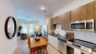 Located at 5111 Abercorn St in Savannah, Georgia, this single-floor, 3-bedroom, 2-bathroom residence offers a thoughtfully designed layout that maximizes comfort and functionality. The open-concept kitchen and living area serves as the heart of the home, featuring a modern kitchen outfitted with stainless steel appliances, dark granite countertops, a white subway tile backsplash, and a stylish combination of white lower cabinetry and warm wood-toned upper cabinets. Light hardwood flooring flows seamlessly through the main living areas, adding warmth and continuity. The living room is bathed in natural light, with French doors opening to a private balcony and offering pleasant outdoor views. The bedrooms are carpeted for comfort, each with large windows that invite in natural light. The primary bedroom includes direct access to a dedicated bathroom and a walk-in closet fitted with wire shelving and organizational features. Both bathrooms are finished with granite countertops, white cabinetry, and clean tile work, with one featuring a full soaking tub. Additional spaces include a dedicated office and a closet, rounding out a versatile and well-equipped floor plan ideal for everyday living in the heart of Savannah.