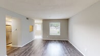 This two-floor residence is designed with a practical and clean aesthetic, offering well-defined living spaces across both levels. The main living areas on the lower floor feature durable wood-look plank flooring in a warm grey tone, complemented by neutral-painted walls and textured ceilings. Natural light filters in through multiple windows fitted with blinds, providing views of the surrounding neighborhood. A staircase connects the two floors, contributing to the open, functional layout visible in the floor plan.

The kitchen is appointed with white shaker-style cabinetry, granite-look countertops, a subway tile backsplash, and stainless steel appliances including a refrigerator, range, and microwave. A herringbone-patterned tile floor adds a refined detail to this efficiently organized space.

The bedrooms are carpeted for comfort, each featuring windows that bring in natural light and views of greenery outside. Two bathrooms serve the residence: one includes a tub-shower combination with a white surround and herringbone tile flooring, while the other features a walk-in shower with white subway tile walls and matching tile flooring. Both bathrooms are finished with clean white fixtures and neutral tones throughout.