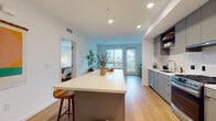 Located at 201 Del Sol Dr in San Diego's Mission Valley neighborhood, this modern single-floor residence offers a thoughtfully designed open-concept layout with clean lines and contemporary finishes throughout. Warm hardwood-style flooring flows seamlessly from the kitchen through the living area, creating a cohesive and inviting atmosphere.

The kitchen is a standout feature, equipped with stainless steel appliances including a gas range, French door refrigerator, and dishwasher. Sleek gray cabinetry pairs with white quartz countertops, and a spacious island with seating provides an ideal space for casual dining or entertaining. The living area receives generous natural light through large windows that frame views of the surrounding neighborhood, including glimpses of palm trees.

Two well-appointed bedrooms offer comfortable retreats, each featuring large windows that bring in ample natural light. The primary bedroom includes dual closets, providing abundant storage. Both bathrooms are finished in a clean, modern style with white quartz vanities, undermount sinks, and contemporary fixtures — one featuring a wall-mounted toilet and the other a tub/shower combination.

Recessed lighting throughout the home ensures a bright, polished ambiance, and the overall design strikes a balance between modern functionality and relaxed San Diego living.