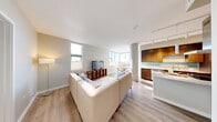 Located at 809 S Washington St in Seattle's vibrant Pioneer Square neighborhood, this thoughtfully designed 2-bedroom, 2-bathroom residence offers a well-appointed single-floor layout. The open-concept living and kitchen area serves as the heart of the home, featuring light wood flooring, exposed concrete columns, and abundant natural light streaming through large windows with city views. The gourmet kitchen is outfitted with rich dark wood cabinetry, a stone-topped island with an integrated cooktop, a stainless steel range hood, and high-end stainless steel appliances, including a full-size refrigerator. A teal glass backsplash adds a modern accent. The living room is bright and airy, with multiple windows framing city skyline views and seamlessly connecting to a dedicated dining area. Both bedrooms feature plush carpeting and natural light; the secondary bedroom offers a particularly striking city view through a generous window. The two bathrooms are finished with clean tile work, including a soaking tub and a glass-enclosed walk-in shower. A dedicated office nook provides a quiet workspace, and two closets offer ample storage. A welcoming entrance hallway with built-in closet storage completes this polished urban residence.