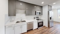 Located at 4900 Spruce St in Philadelphia's West Philadelphia neighborhood, this thoughtfully designed 2-bedroom, 2-bathroom unit offers a contemporary living experience on a single floor. Warm hardwood flooring runs throughout, tying together a clean, modern aesthetic.

The open-concept kitchen is a standout feature, showcasing high-gloss gray upper cabinetry, crisp white lower cabinets, and a sleek marble-style backsplash and countertops. A full suite of stainless steel appliances—including a range, over-the-range microwave, dishwasher, and French door refrigerator—completes the space. Recessed lighting enhances the kitchen's polished finish.

The living area flows naturally from the kitchen and is anchored by a large picture window offering impressive views of the Philadelphia skyline and surrounding neighborhood. A ceiling fan adds both function and style.

Both bedrooms are bright and airy, each equipped with a ceiling fan and multiple windows that frame expansive city and treetop views, filling the rooms with abundant natural light. A well-lit hallway with recessed lighting connects the private areas of the unit.

The bathrooms are elegantly finished with marble-style floor and wall tiles. One bathroom features a frameless glass sliding door enclosing a tub-shower combination, while the other offers a sleek walk-in shower with a linear drain—both reflecting a high level of contemporary craftsmanship.