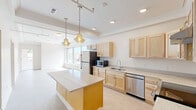 Located at 509 9th St in De Witt, Iowa, this single-floor, 3-bedroom, 2-bathroom residence offers a thoughtfully designed layout with a clean, modern aesthetic throughout. The open kitchen is a standout feature, equipped with light maple cabinetry, granite-style countertops, a center island with pendant lighting, and a full suite of stainless steel appliances including a refrigerator, dishwasher, and range. Recessed lighting and a large window flood the kitchen and adjoining living area with natural light, creating a bright and welcoming atmosphere. The three bedrooms are generously proportioned, with the primary bedroom showcasing an elegant tray ceiling and large windows that invite abundant daylight. Additional bedrooms also benefit from oversized windows offering views of the surrounding De Witt community. The bathrooms are finished with light tile flooring, granite-style countertops, and accessible features including grab bars and a walk-in shower, reflecting a practical and inclusive design. A dedicated in-unit laundry room with a full-size front-loading washer and dryer adds everyday convenience. Soft carpeting in the bedrooms and neutral tones throughout give the entire space a cohesive, comfortable feel.