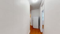 Located at 11 Tetlow St in Boston's Fenway neighborhood, this one-bedroom, one-bathroom unit offers a well-organized layout across a single floor, comprising a living room, bedroom, kitchen, bathroom, hallway, and two closets. Warm hardwood floors run throughout, lending a consistent and classic character to the space.

The living room features a charming bay window configuration, allowing natural light to fill the room from multiple angles and offering views of the surrounding neighborhood. The bedroom is a comfortable size, equipped with a cast-iron radiator and two windows that provide ample light and ventilation. A separate, smaller room with a window offers flexible use as a home office or additional storage.

The kitchen is fitted with honey-toned wood cabinetry, white countertops, and a window above the counter that brings in natural light. A standard range is included. The hallway connects the rooms efficiently, with closets providing practical storage solutions.

The bathroom retains a classic aesthetic with square floor tiles, subway-style wall tiles, and a full soaking tub. A window adds natural light and ventilation to the space. Throughout the unit, white walls and traditional trim work reflect the building's period character, creating a bright and cohesive atmosphere.
