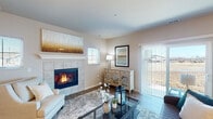 This thoughtfully designed single-floor residence offers a comfortable and cohesive layout across a collection of well-appointed rooms. The living room serves as the heart of the home, anchored by a striking tile-surround fireplace and complemented by rich hardwood-style flooring, abundant natural light from multiple windows, and direct access to the outdoors through a sliding glass door with vertical blinds. The space flows naturally into a dedicated dining area, where a corner window arrangement invites plenty of daylight and outdoor views, creating an ideal setting for everyday meals. The kitchen features crisp white shaker cabinetry extending to the ceiling for ample storage, paired with stainless steel appliances including a refrigerator, electric range, and built-in microwave, all set above warm wood-look flooring. Two well-sized bedrooms each offer plush carpeting, ceiling fans with light fixtures, and large windows that frame outdoor views. Both bathrooms are finished with white vanity cabinetry, wood-look tile flooring, and clean neutral walls; one includes a glass-enclosed shower while the other features a shower-tub combination. Throughout the residence, a consistent warm neutral palette and cohesive finishes create a calm, move-in-ready ambiance.