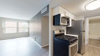 This 2-bedroom, 1-bathroom unit offers a thoughtfully designed single-floor layout with contemporary finishes throughout. The galley-style kitchen is a standout feature, showcasing white shaker cabinets with brushed gold hardware, light quartz countertops, a mosaic tile backsplash, and a full suite of stainless steel appliances including a gas range, over-the-range microwave, refrigerator, and dishwasher. The kitchen opens toward the living area, which is accented by a bold gray accent wall and flows seamlessly throughout the space. Wide-plank wood-style flooring runs throughout the entire unit, adding warmth and visual continuity. Both bedrooms are generously proportioned with neutral wall tones and large windows that invite natural light and offer views of the surrounding neighborhood. The full bathroom features white subway tile surrounding the tub/shower combo, a white vanity with dark countertop and brushed nickel hardware, and matching wood-style flooring that ties into the rest of the home. Ceiling-mounted light fixtures, ample closet space, and multiple windows across the unit contribute to a bright, functional, and move-in-ready living environment.
