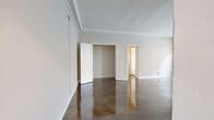 Located at 900 S Serrano Ave in Los Angeles, this 1-bedroom, 1-bathroom unit offers a thoughtfully laid-out single-floor plan with classic architectural character. Gleaming polished concrete floors run throughout, reflecting light and lending a sleek, modern contrast to the space's vintage detailing. The living area is a standout, featuring an ornate white decorative fireplace with carved molding, intricate crown molding along the ceiling, a traditional cast-iron radiator, and large windows that invite natural light. An elegant arched doorway connects the living area to the kitchen, which is outfitted with white cabinetry, granite-style countertops, a gas range, and ample storage. The generously sized bedroom includes a dedicated closet with built-in shelving and hanging rods. The hallway features a charming built-in vanity with a mirror and sconce lighting, leading into the bathroom, which retains a classic aesthetic with a pedestal sink, tiled flooring in a soft green hue, and period-appropriate fixtures. A walk-in closet provides additional storage. The overall ambiance is one of timeless Los Angeles character, blending vintage craftsmanship with functional, updated living spaces.