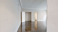 Located at 900 S Serrano Ave in Los Angeles, this 1-bedroom, 1-bathroom unit offers a thoughtfully laid-out single-floor plan with classic architectural character. Gleaming polished concrete floors run throughout, reflecting light and lending a sleek, modern contrast to the space's vintage detailing. The living area is a standout, featuring an ornate white decorative fireplace with carved molding, intricate crown molding along the ceiling, a traditional cast-iron radiator, and large windows that invite natural light. An elegant arched doorway connects the living area to the kitchen, which is outfitted with white cabinetry, granite-style countertops, a gas range, and ample storage. The generously sized bedroom includes a dedicated closet with built-in shelving and hanging rods. The hallway features a charming built-in vanity with a mirror and sconce lighting, leading into the bathroom, which retains a classic aesthetic with a pedestal sink, tiled flooring in a soft green hue, and period-appropriate fixtures. A walk-in closet provides additional storage. The overall ambiance is one of timeless Los Angeles character, blending vintage craftsmanship with functional, updated living spaces.