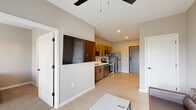 Located at 353 Vine St in West Lafayette, Indiana, this well-appointed one-bedroom, one-bathroom unit offers a thoughtfully designed layout across a single floor. The open-concept kitchen and living area serves as the heart of the space, featuring light wood-toned cabinetry, white quartz countertops, and a full suite of stainless steel appliances including a refrigerator, electric range, over-the-range microwave, and dishwasher. Light wood-style flooring runs throughout the main living area, complementing the neutral warm-gray walls and clean-lined modern aesthetic. The living room benefits from abundant natural light through floor-to-ceiling glass doors that open to a private balcony, fitted with vertical blinds for privacy control. A ceiling fan with overhead lighting anchors the space. The bedroom is carpeted for comfort, includes a ceiling fan, a window with outdoor views, and connects directly to a spacious walk-in closet outfitted with wire shelving. The full bathroom is conveniently accessible from the bedroom corridor. An additional closet and a dedicated in-unit laundry area provide practical storage and convenience. The overall design is modern and functional, with consistent finishes throughout that create a cohesive, move-in-ready living environment.