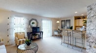 This single-floor residence offers a thoughtfully designed layout that balances comfort and functionality throughout. The open-concept living room is a welcoming centerpiece, featuring plush carpeting, a textured ceiling, and an abundance of natural light streaming through large windows and a sliding glass door. The living area flows seamlessly into the dining space, which is anchored by a pendant light and provides direct access to a private balcony overlooking lush greenery and neighboring buildings.

The kitchen is efficiently arranged with light wood cabinetry extending to the ceiling, recessed lighting, a white appliance suite including a range, microwave, and refrigerator, and a breakfast bar that connects to the dining area. Hardwood-style flooring adds warmth to the kitchen space.

The residence includes two carpeted bedrooms, each filled with natural light from well-placed windows. The primary bedroom features a walk-in closet with mirrored bifold doors, while the second bedroom makes a bold design statement with a striking floral-patterned accent wall. The full bathroom is finished with wood-toned cabinetry, a combined tub and shower, and durable wood-look flooring, completing this comfortable and stylish home.