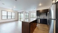 This well-designed single-floor residence offers a thoughtfully laid-out open-concept living space bathed in natural light. The kitchen serves as the heart of the home, showcasing dark espresso cabinetry, a striking granite-topped center island, a gray brick-style tile backsplash, and stainless steel appliances including a refrigerator and dishwasher. Wood-look flooring flows throughout the main living areas, complementing the clean white walls and recessed lighting overhead. Large windows and a sliding glass door in the living area invite abundant natural light and provide outdoor views, enhancing the airy feel of the space. The bedrooms feature plush carpeting, ceiling fans, and windows that continue to bring in natural light. A spacious walk-in closet with built-in shelving and hanging rods offers generous storage. The primary bathroom includes a soaking tub, a separate tiled shower, wood-look flooring, and dark cabinetry topped with granite. A second full bathroom mirrors the refined finishes with a granite vanity, dark cabinetry, and a tub-shower combination. Hallways are bright and open, connecting each area with ease. Throughout, the design balances modern finishes with functional detail, creating a cohesive and comfortable living environment.