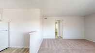 This 2-bedroom, 1-bathroom single-floor unit offers a straightforward and functional layout designed to maximize every square foot. The living room serves as the central gathering space, featuring soft carpeting, neutral-toned walls, a textured ceiling, and a low partition wall that subtly defines the entry area while maintaining an open feel. Natural light filters in through vertical-blind-covered windows, creating a bright and airy atmosphere throughout.

The kitchen is efficiently appointed with white cabinetry, dark countertops, wood-look flooring, and a full suite of white appliances including an electric range, refrigerator, and built-in range hood. A sink with adjacent counter space adds practical functionality to the cooking area.

Both bedrooms are carpeted and finished with neutral walls and textured ceilings. The primary bedroom offers a comfortable footprint with a window that brings in natural light and views of surrounding greenery. The second bedroom mirrors this layout with its own window and closet access. Each room provides a calm, clean environment well-suited for rest.

The bathroom is neatly finished with a white vanity, wood-look flooring, and a full tub-shower combination with chrome fixtures. A hallway connects the main living areas to the bedrooms and bathroom, with two closets providing additional storage throughout the unit.