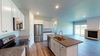 This single-floor unit offers a well-designed layout with consistent finishes throughout. The kitchen serves as a central highlight, featuring white shaker-style cabinetry extending to the ceiling, dark granite countertops, and a full suite of stainless steel appliances including a French door refrigerator, electric range, built-in microwave, and dishwasher. A central island with an undermount sink provides additional workspace and storage, while wood-style plank flooring adds warmth to the space.

The living area connects openly to the kitchen and receives natural light through a sliding glass door that leads to an outdoor area. The bedrooms are comfortably proportioned, each equipped with a ceiling fan and windows framing scenic outdoor views of surrounding greenery. Baseboard heating units are present throughout.

Two bathrooms serve the unit. The full bathroom includes a tub-shower combination and granite-topped vanity with white cabinetry, while the half bathroom features a matching granite vanity, undermount sink, and large mirror. Neutral-toned walls paired with wood-style flooring carried throughout the unit create a cohesive, clean aesthetic suited to a variety of interior styles.