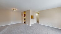 This single-floor residence offers a practical and comfortable layout across two bedrooms and two bathrooms. The open living area features neutral-toned walls and plush wall-to-wall carpeting, creating a warm and inviting atmosphere. A large window allows natural light to fill the space, enhancing the airy feel of the room. The kitchen is designed in a galley style, featuring rich dark wood cabinetry, granite-look countertops, a classic white subway tile backsplash, hardwood-style flooring, and white appliances including a range and refrigerator. A pass-through counter connects the kitchen to the living area, adding an open, communicative flow between spaces. The primary bedroom is generously sized, complete with a ceiling fan, a closet, and direct access to a private en-suite bathroom. The en-suite features a dark wood vanity with a granite-style countertop, and a tub-shower combination with white tile surround. The second bedroom also offers comfortable proportions, carpeted flooring, a ceiling fan, and a sliding-door closet. The second bathroom mirrors the clean design of the first, with a tiled tub-shower combo and hardwood-style flooring. Throughout, the consistent warm beige palette and thoughtful layout contribute to a cohesive and livable environment.