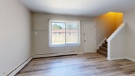 Located at 957 N Perry St in Pontiac, Michigan, this two-bedroom, one-bathroom unit spans two floors, offering a practical and well-organized layout. The main floor includes a welcoming living room with large windows fitted with vertical blinds, allowing ample natural light to fill the space. A carpeted staircase leads to the upper level. The kitchen is equipped with white cabinetry, a double stainless steel sink, light countertops, and a refrigerator, providing functional storage and workspace. Throughout the unit, light wood-style vinyl flooring adds a clean, modern aesthetic and continuity between rooms. Baseboard heating is present throughout, ensuring comfort year-round. Both bedrooms are well-proportioned, with the primary bedroom offering a comfortable footprint. A notable feature is the mirrored sliding closet doors found in the bedrooms, which enhance the sense of space. The full bathroom is outfitted with a tub-shower combination featuring a white surround with built-in shelving niches and chrome fixtures. Neutral wall tones and clean finishes give the unit a fresh, move-in-ready appearance, making it a straightforward and functional two-story home.