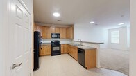 Located at 4640 Daisy Reid Ave, Unit 306 in Woodbridge, Virginia, this one-bedroom, one-bathroom residence offers a thoughtfully organized single-level layout. The open-concept kitchen and living area serves as the heart of the home, where the kitchen is equipped with warm honey-toned cabinetry, black appliances including a refrigerator, range, microwave, and dishwasher, and granite-style countertops. A peninsula with bar seating and an integrated sink seamlessly connects the kitchen to the living area, making the space ideal for both cooking and entertaining. Light ceramic tile flooring runs throughout the kitchen, providing a clean, durable surface. The generously sized bedroom features plush wall-to-wall carpeting, crisp white walls, and multiple windows fitted with blinds that allow for ample natural light and outdoor views. A built-in window bench adds a functional architectural detail to the bedroom. A dedicated closet provides convenient storage. The bathroom includes a warm wood-toned vanity with countertop, tile flooring, and a clean, straightforward layout. Throughout the residence, neutral tones and consistent finishes create a cohesive and welcoming atmosphere.
