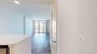 This 620 square foot apartment offers a thoughtful blend of comfort and functionality. The space comprises two bedrooms, including a primary bedroom of 130 square feet, and two full bathrooms. The single-floor layout is designed for efficiency, featuring a combined kitchen and living room area that serves as the heart of the home.

The kitchen boasts modern amenities with sleek, dark wood cabinetry, stainless steel appliances, and a light-colored quartz countertop. A subway tile backsplash adds a touch of contemporary style. The open concept flows seamlessly into the living area, which is bathed in natural light from large windows offering impressive city views.

Throughout the apartment, warm-toned wood flooring creates a cohesive and inviting atmosphere. The bedrooms, while compact, are well-proportioned and include ample closet space. The bathrooms feature modern fixtures and neutral tiling, with at least one including a bathtub.

The apartment's design maximizes space utilization, with clever storage solutions and a layout that feels open despite its modest square footage. Recessed lighting and white walls contribute to a bright, airy ambiance throughout. This urban dwelling is ideal for those seeking a modern, low-maintenance lifestyle in the heart of the city.