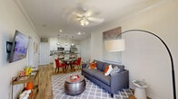 Located at 1699 Chatham Pkwy in Savannah, Georgia, this well-appointed 2-bedroom, 2-bathroom residence offers a thoughtfully designed single-level layout. The open-concept living, dining, and kitchen area serves as the heart of the home, finished with warm wood-look flooring, crown molding, and a ceiling fan overhead. The kitchen stands out with white shaker cabinetry, dark granite countertops, stainless steel appliances including a refrigerator and microwave, a breakfast bar with pendant lighting, and a built-in wine rack — combining style and function seamlessly. The dining area flows naturally into the living room, creating an inviting space for entertaining. The primary bedroom features plush carpeting, a ceiling fan, and a large window that fills the room with natural light and views of lush greenery. A boldly accented walk-in closet with built-in shelving provides ample storage. The bathrooms are finished with granite-topped vanities and wood-look tile flooring, with one featuring a tub/shower combination. A convenient in-unit laundry area with a full-size washer and dryer adds everyday practicality. Crown molding and recessed lighting throughout lend a polished, cohesive feel to the entire home.