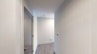 Located in the heart of downtown Raleigh on Fayetteville Street, this modern 2-bedroom, 2-bathroom residence offers a sleek, contemporary living experience across a well-appointed single floor. The open-concept kitchen and living area is a standout, featuring floor-to-ceiling windows that flood the space with natural light and frame impressive views of the Raleigh skyline. The kitchen is outfitted with stainless steel appliances, light wood cabinetry, and clean white countertops, flowing seamlessly into the living area. A distinctive structural column adds an architectural accent to the living space. Light wood-tone flooring runs throughout, complementing the bright, neutral palette of the interiors. Both bedrooms are generously sized, each offering ceiling fans and large windows with city views — the primary bedroom benefiting from an especially expansive window wall. The two bathrooms are finished with neutral tile flooring, modern vanities with ample storage, and glass-enclosed showers. A dedicated closet and hallway provide functional storage and connectivity between rooms. The overall ambiance is clean, airy, and urban, making this a well-suited residence for those seeking modern downtown living in Raleigh.