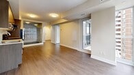 This thoughtfully laid-out 2-bedroom, 1-bathroom unit offers a modern, clean aesthetic throughout its single floor. Hardwood-style flooring flows consistently across all rooms, lending a cohesive and contemporary feel to the space.

The open-concept kitchen and living area serves as the heart of the unit. The kitchen is outfitted with stainless steel appliances — including a refrigerator, range, and dishwasher — paired with dark wood cabinetry, light countertops, and a classic white subway tile backsplash. A glass partition between the kitchen and living area enhances the sense of openness while maintaining definition between the two spaces.

The living room benefits from expansive floor-to-ceiling windows that frame impressive city skyline views, allowing abundant natural light to fill the room. Access to a balcony further extends the living space outdoors.

Both bedrooms feature the same hardwood-style flooring and neutral wall tones, creating calm, versatile spaces. The primary bedroom includes large windows with urban views, while the second bedroom offers a closet and direct sightlines to the kitchen area.

The bathroom is finished with clean white tile surrounding a full soaking tub and shower combination, maintaining the unit's consistent, modern style. A dedicated hallway closet provides additional storage.