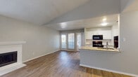 This single-story unit offers a well-organized layout with distinct living, kitchen, bedroom, and bathroom areas. The living room is a standout space, characterized by vaulted ceilings, wood-look flooring, and a classic fireplace framed by a white mantel. Natural light filters in through a large window, enhancing the open, airy feel of the room. An adjoining dining and kitchen area features an open-concept design with a peninsula counter topped in granite, white cabinetry with a subway tile backsplash, and black appliances including a range, microwave, dishwasher, and refrigerator. Wood-look flooring continues throughout the main living areas, providing a cohesive aesthetic.

The bedrooms are carpeted and generously sized, each offering ceiling fans and natural light from windows with blinds. At least one bedroom includes access to a walk-in closet. The unit includes two full bathrooms, each finished with granite-topped vanities, white cabinetry, wood-look tile flooring, and a tub-shower combination. Textured ceilings are present throughout, and neutral wall tones create a clean, move-in-ready atmosphere across the entire unit.