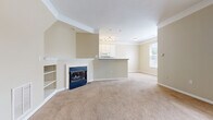 Located at 7200 Gorden Farms Parkway in Dublin, OH, this two-story, 2-bedroom, 2-bathroom home offers a well-organized layout across two floors. The main level opens with a welcoming entrance that leads into a spacious combined living room and kitchen area. The living room features soaring vaulted ceilings, neutral-toned carpet, crown molding, and a classic fireplace flanked by built-in shelving — a standout focal point of the space. The kitchen is equipped with white cabinetry, laminate countertops, white appliances including a range and built-in microwave, and tile flooring, with a pass-through bar connecting it to the living area. A utility room and half bathroom with tile flooring round out the first floor. Upstairs, two carpeted bedrooms offer comfortable retreats, each with natural light from large windows and closet access. The primary bedroom is generously sized with crown molding details. The primary bathroom includes a soaking tub, a separate glass-enclosed shower, a vanity with white cabinetry, and tile flooring. A second full bathroom serves the additional bedroom. The home maintains a consistent warm, neutral palette throughout, creating a cohesive and inviting atmosphere.